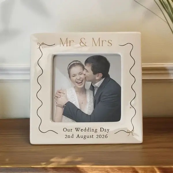 A personalised square wedding photo frame reading Mr & Mrs and Our Wedding Day with a date, displaying a couple’s wedding photo on a wooden surface.
